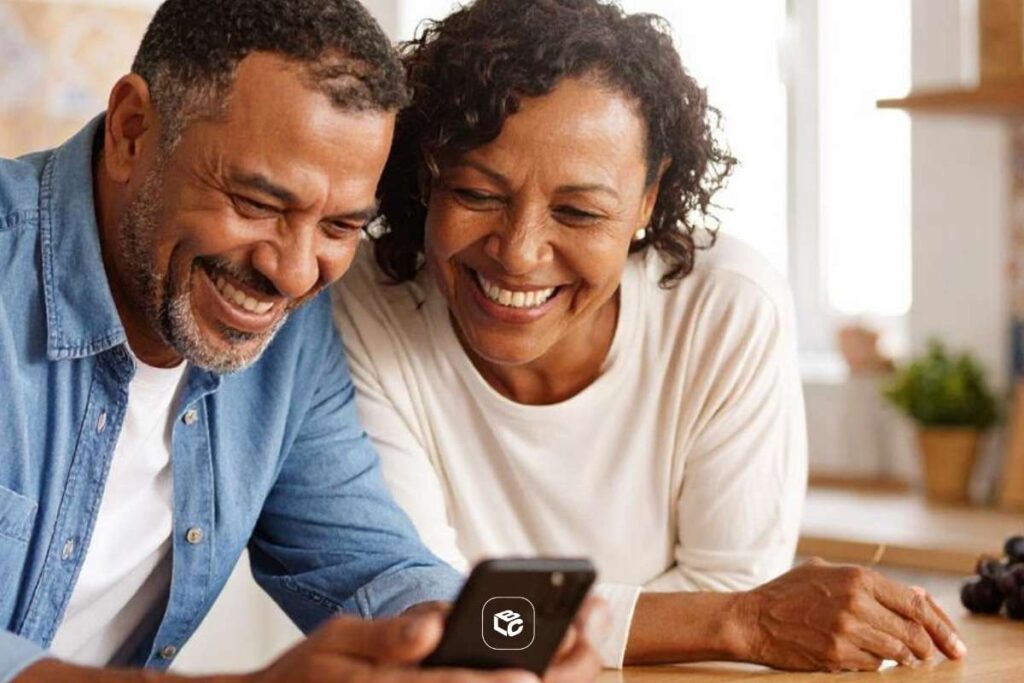 Casal negro sorrindo ao olhar um celular. LCbank: escolha estratégica para quem antecipa RPV.