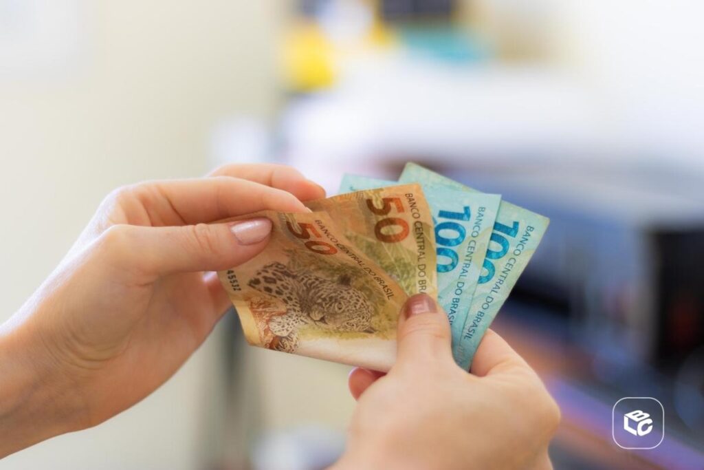 Mãos segurando notas de 50 e 100 reais, simulando valor de RPV