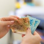 Mãos segurando notas de 50 e 100 reais, simulando valor de RPV